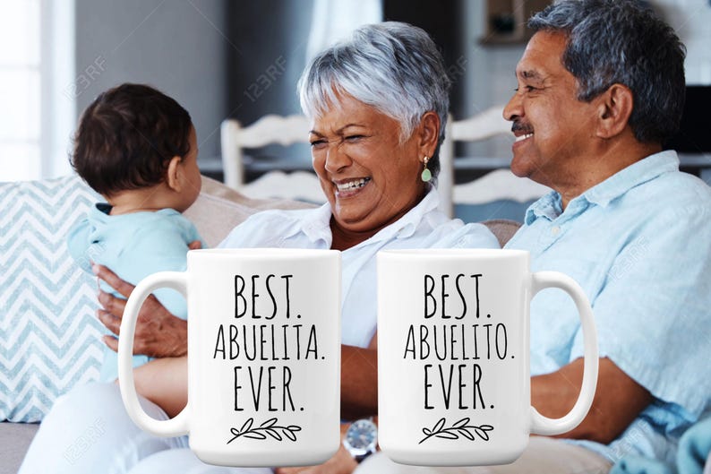 Peut inclure: Deux tasses en c&eacute;ramique blanche avec du texte noir et un petit motif de feuille. La tasse de gauche dit "Best Abuelita Ever." La tasse de droite dit "Best Abuelito Ever."