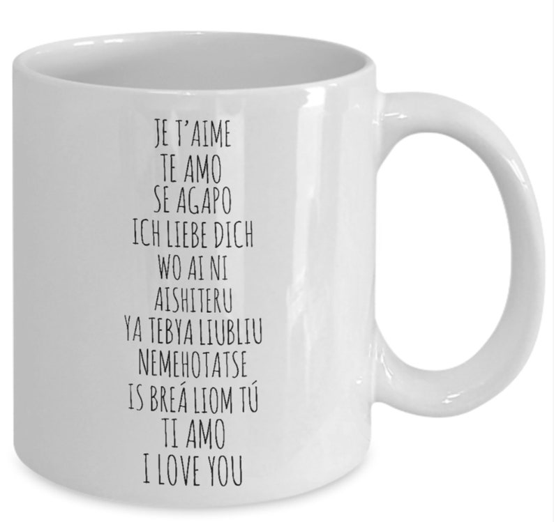 May include: White ceramic coffee mug with black text that reads "Je t'aime", "Te amo", "Se Agapo", "Ich liebe dich", "Wo ai ni", "Aishiteru", "Ya tebya liubliu", "Nemehotatse", "Is bre&aacute; liom t&uacute;", "Ti amo", "I love you".