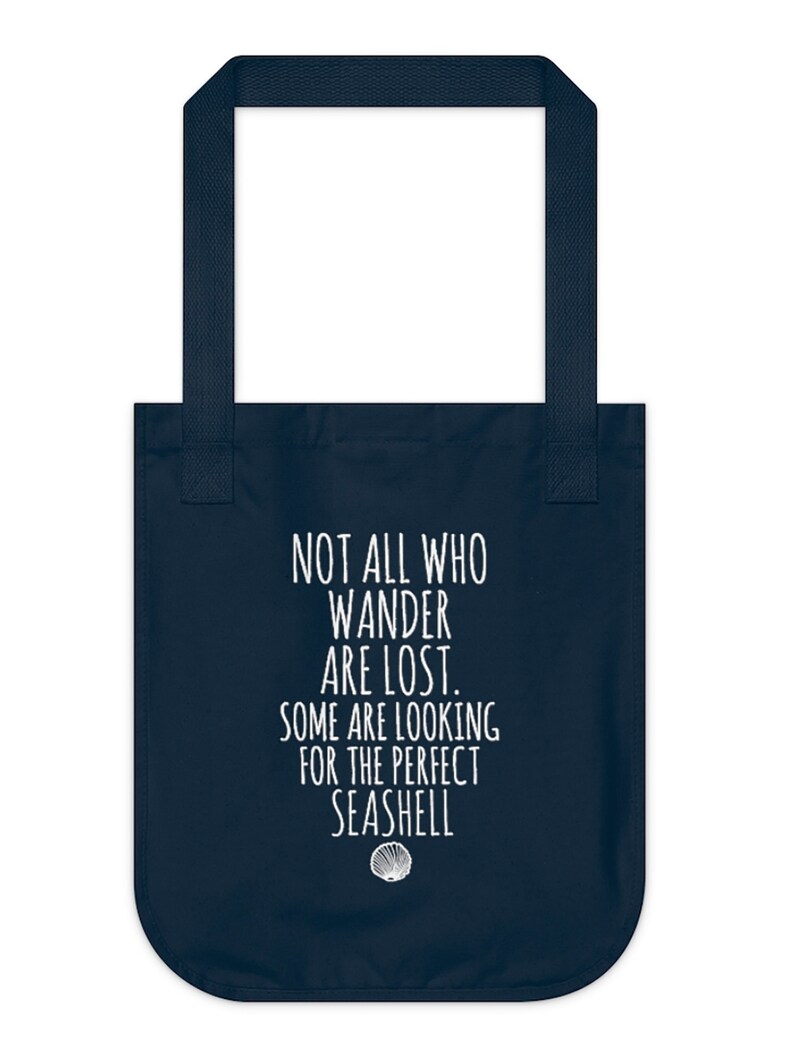 May include: Navy blue tote bag with white text that reads "Not all who wander are lost. Some are looking for the perfect seashell." A white seashell icon is below the text.