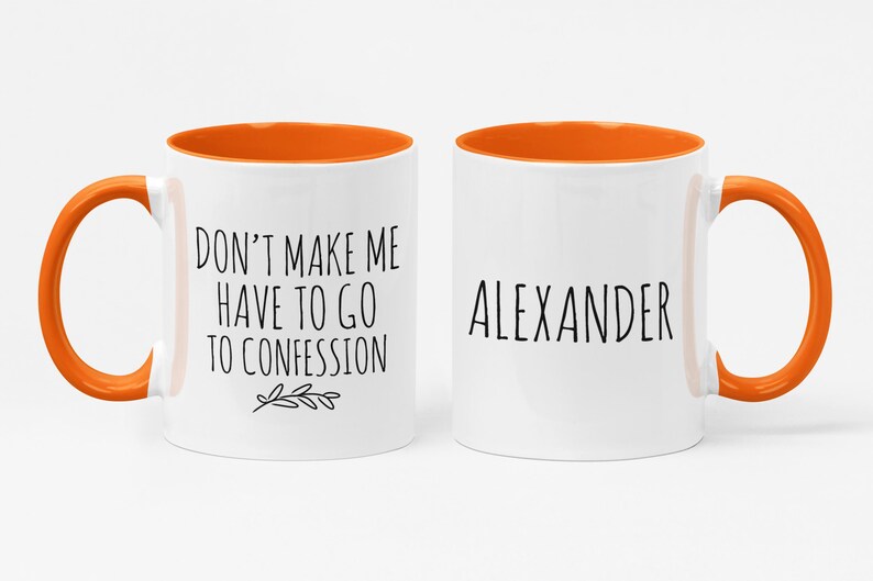 May include: Two white ceramic mugs with orange interiors and handles. One mug reads "DON'T MAKE ME HAVE TO GO TO CONFESSION" with a leaf design. The other mug has the name "ALEXANDER" in black text.