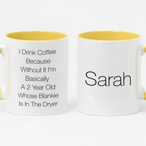 May include: A white coffee mug with a yellow rim and handle. The mug has text that reads "I Drink Coffee Because Without It I'm Basically A 2 Year Old Whose Blankie Is In The Dryer". The other side of the mug has the name "Sarah" written in black.