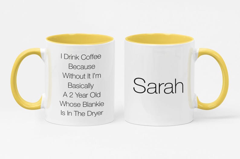 May include: A white coffee mug with a yellow rim and handle. The mug has text that reads "I Drink Coffee Because Without It I'm Basically A 2 Year Old Whose Blankie Is In The Dryer". The other side of the mug has the name "Sarah" written in black.