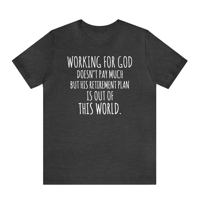 May include: Dark heather grey t-shirt with white text that reads "WORKING FOR GOD DOESN'T PAY MUCH BUT HIS RETIREMENT PLAN IS OUT OF THIS WORLD."