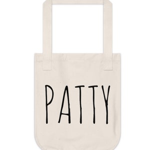May include: A white canvas tote bag with black handles and the word "PATTY" printed in black on the front.