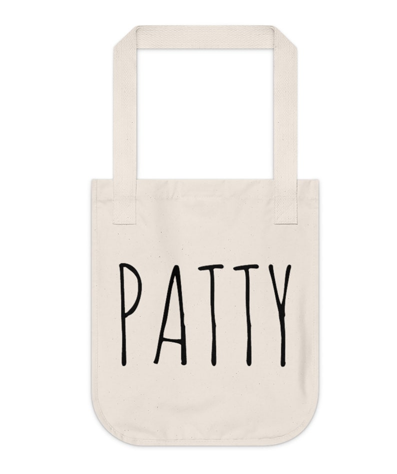 May include: A white canvas tote bag with black handles and the word "PATTY" printed in black on the front.