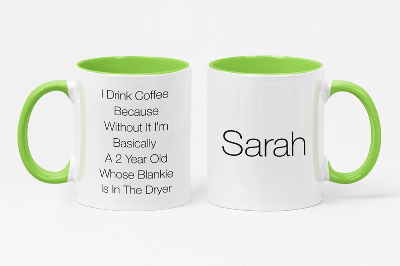 May include: White ceramic coffee mug with a green rim and handle. The mug has text that reads "I Drink Coffee Because Without It I'm Basically A 2 Year Old Whose Blankie Is In The Dryer". The other side of the mug has the name "Sarah" printed on it.