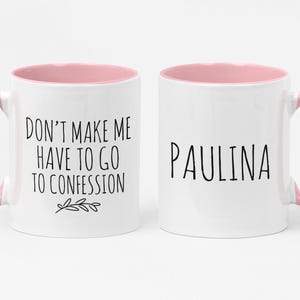 May include: Two white ceramic mugs with pink handles and interiors. One mug reads "DON'T MAKE ME HAVE TO GO TO CONFESSION" in black text, the other says "PAULINA". A simple, fun gift idea.