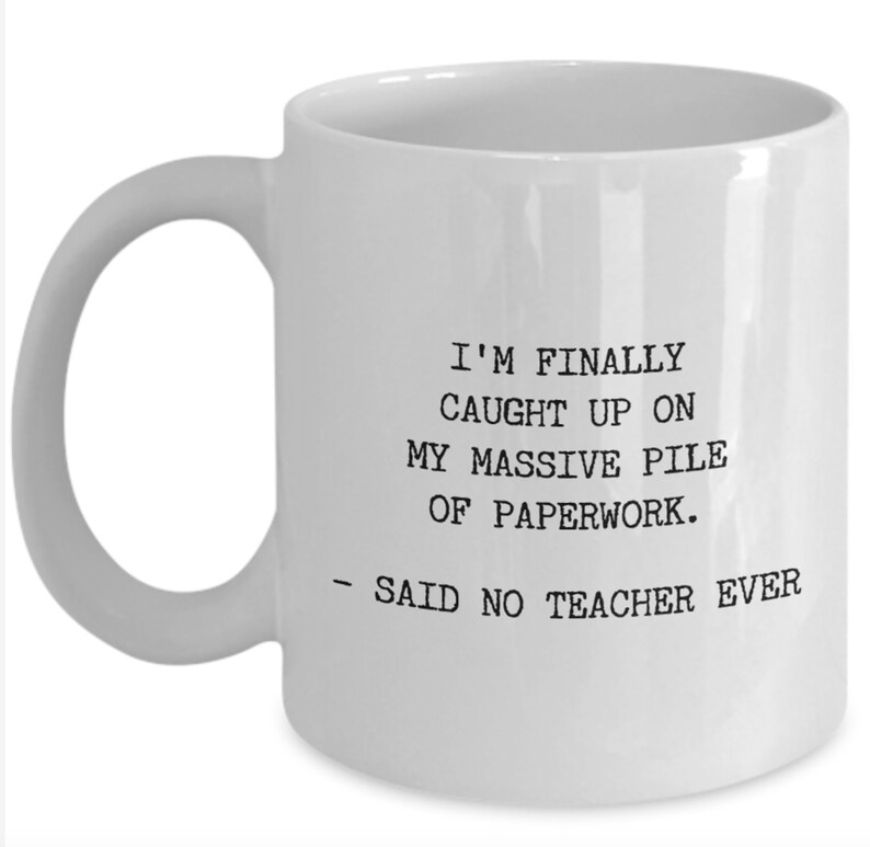 May include: White ceramic coffee mug with black text that reads: "I'm finally caught up on my massive pile of paperwork. - Said no teacher ever."