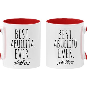 Peut inclure: Deux tasses en c&eacute;ramique blanche avec int&eacute;rieur et poign&eacute;es rouges. La tasse de gauche dit "Best Abuelita Ever." La tasse de droite dit "Best Abuelito Ever."