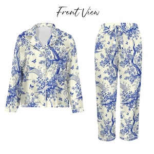May include: A two-piece pyjama set with a blue and white toile design. The long-sleeved top has a button-down front and a notched collar. The trousers have a drawstring waist. The set is made of a soft, lightweight fabric.