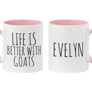 May include: Two white ceramic mugs with pink rims. One mug says "Life is better with goats" and the other mug says "Evelyn".