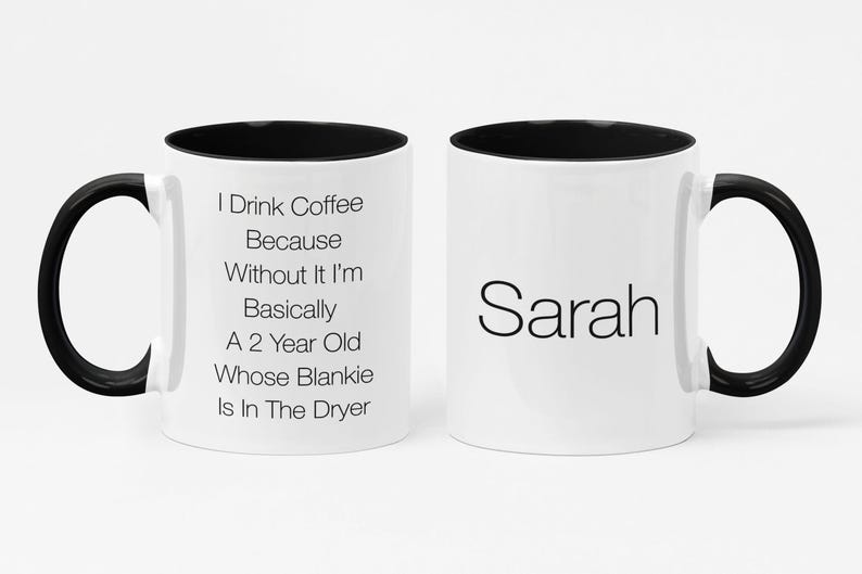May include: White ceramic coffee mug with a black rim and handle. The mug has black text that reads "I Drink Coffee Because Without It I'm Basically A 2 Year Old Whose Blankie Is In The Dryer". The other side of the mug has the name "Sarah" in black text.