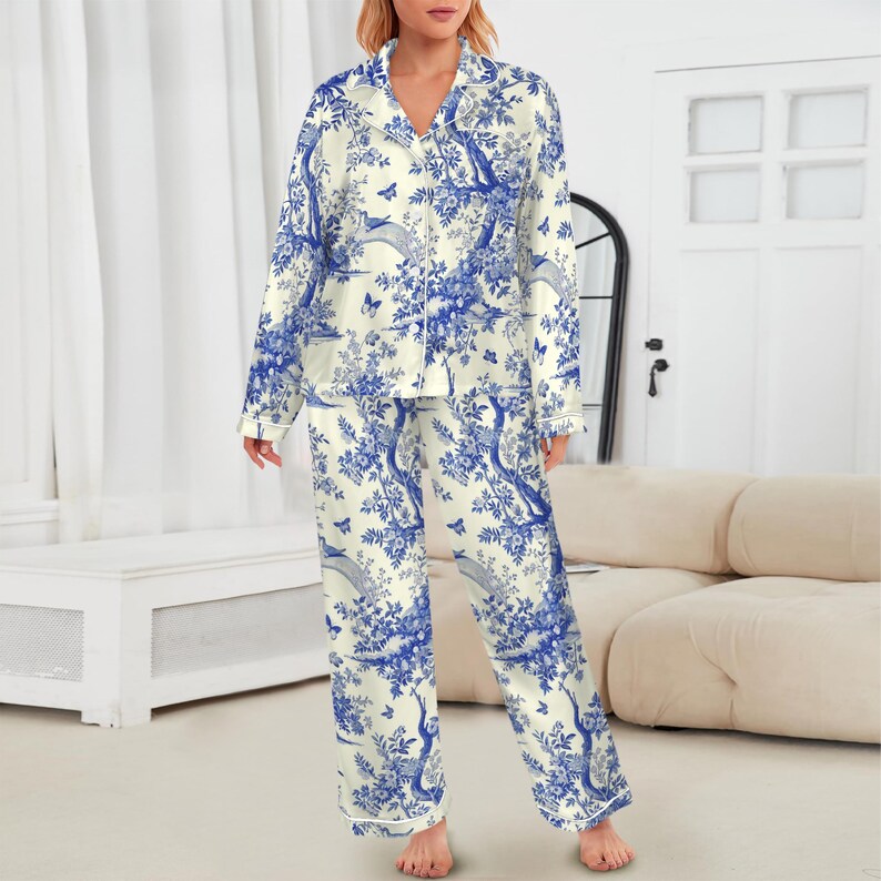 May include: Cream-coloured two-piece pyjama set with a blue floral and bird design. The long-sleeved top has a notched collar and button-down front. The trousers are long and straight-legged. The set is made of a soft, lightweight fabric.