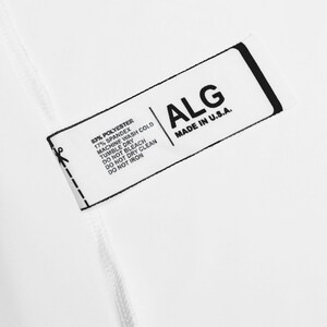 May include: A white rectangular clothing tag with black text. The tag displays the brand name ALG, MADE IN U.S.A., and fabric content of 83% POLYESTER, 17% SPANDEX. Care instructions include MACHINE WASH COLD, TUMBLE DRY, DO NOT BLEACH, DO NOT DRY CLEAN, DO NOT IRON.