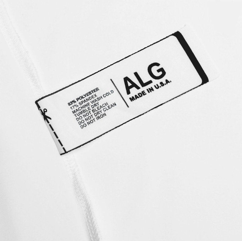 May include: A white rectangular clothing tag with black text. The tag displays the brand name ALG, MADE IN U.S.A., and fabric content of 83% POLYESTER, 17% SPANDEX. Care instructions include MACHINE WASH COLD, TUMBLE DRY, DO NOT BLEACH, DO NOT DRY CLEAN, DO NOT IRON.