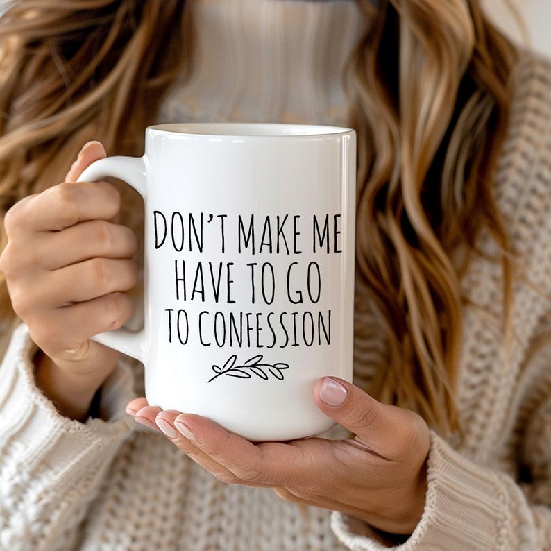 May include: White ceramic mug with the text "DON'T MAKE ME HAVE TO GO TO CONFESSION" in black, with a small leaf design. The mug has a large handle and is held by a person wearing a beige sweater.