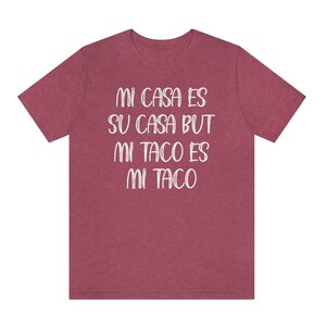 Puede incluir: Una camiseta color granate con el texto "Mi casa es su casa but mi taco es mi taco" impreso en blanco.