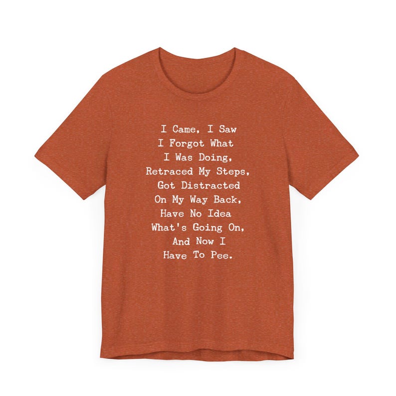 May include: Rust-colored t-shirt with the text "I Came, I Saw, I Forgot What I Was Doing... And Now I Have To Pee." The shirt has a crew neck and short sleeves. The text is in a simple, sans-serif font.