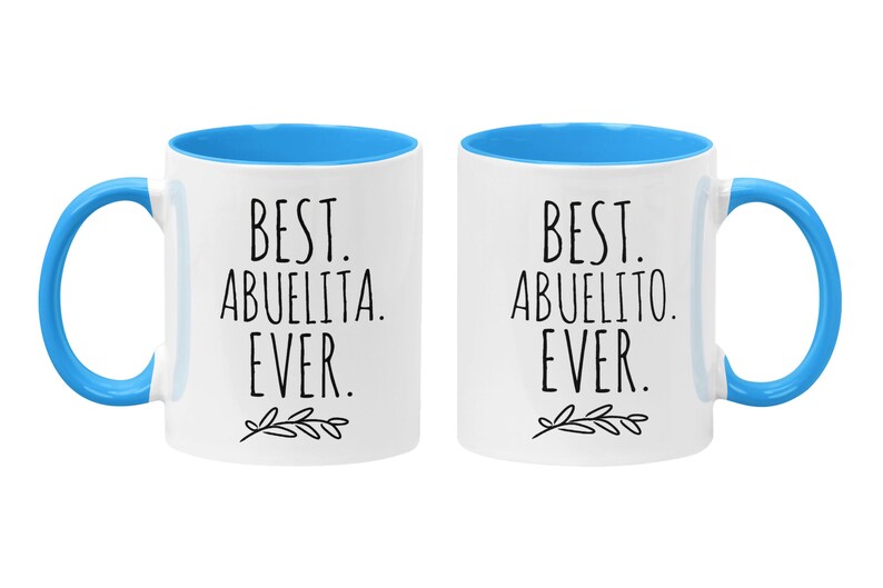 Peut inclure: Deux tasses en c&eacute;ramique blanche avec des bords et des poign&eacute;es bleus. La tasse de gauche dit "Best Abuelita Ever." La tasse de droite dit "Best Abuelito Ever."