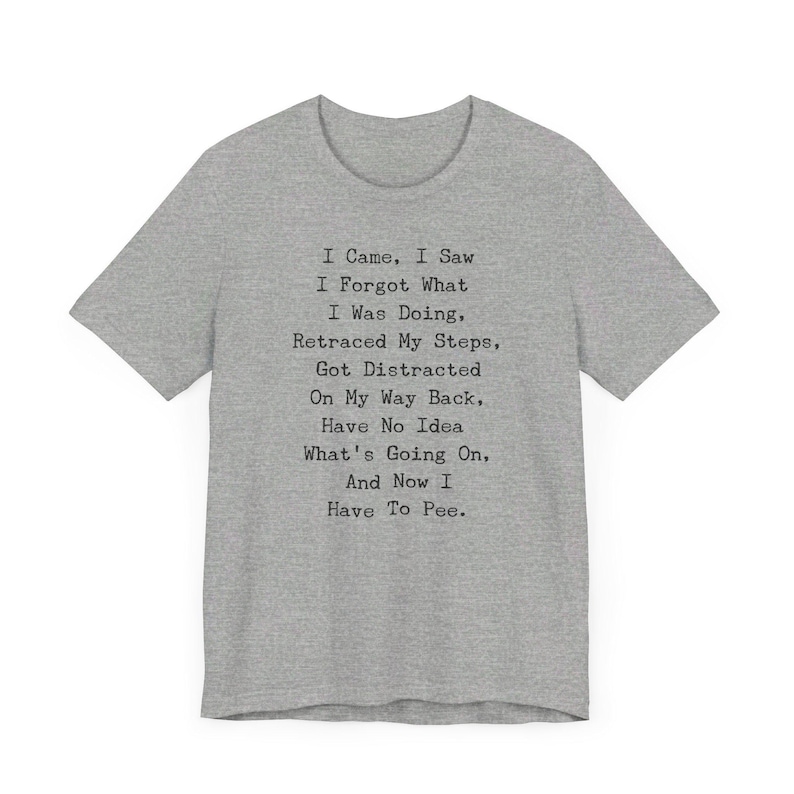 May include: A heather gray t-shirt with the text "I Came, I Saw, I Forgot What I Was Doing, Retraced My Steps, Got Distracted On My Way Back, Have No Idea What's Going On, And Now I Have To Pee." The shirt has short sleeves and a crew neck.