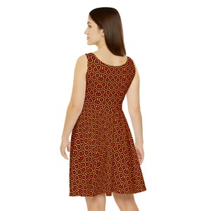 May include: A sleeveless dress featuring a repeating geometric pattern of black hexagons outlined in orange with small red circles centered within each shape. The dress has a scoop neckline and a flared skirt that falls above the knee.