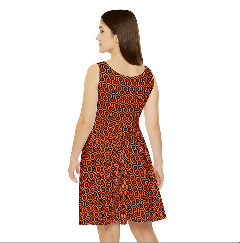May include: A sleeveless dress featuring a repeating geometric pattern of black hexagons outlined in orange with small red circles centered within each shape. The dress has a scoop neckline and a flared skirt that falls above the knee.