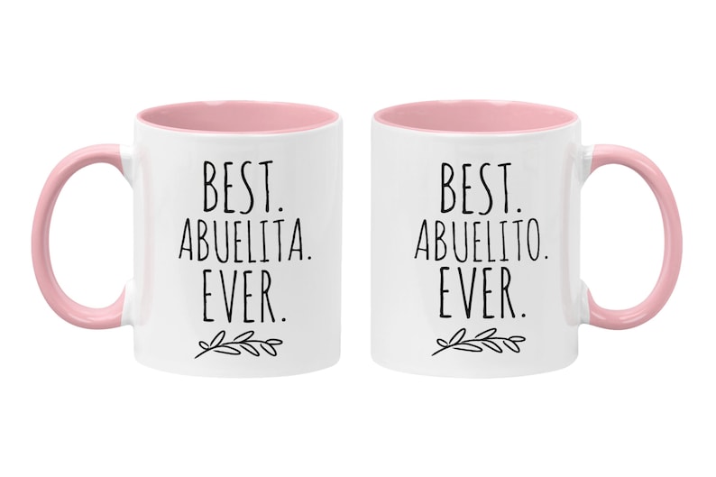 Peut inclure: Deux tasses en c&eacute;ramique blanche avec des bords et des poign&eacute;es roses. La tasse de gauche dit "Best Abuelita Ever." La tasse de droite dit "Best Abuelito Ever."