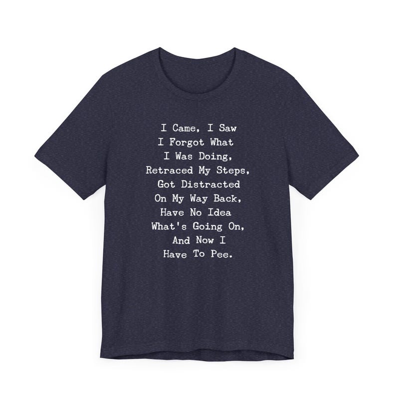May include: Navy blue t-shirt with the text "I Came, I Saw, I Forgot What I Was Doing... And Now I Have To Pee." The text is in a white, typewriter-style font. The shirt has a crew neck and short sleeves.