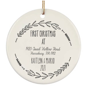 May include: White ceramic Christmas ornament with black text that reads "First Christmas at 1420 Quail Hollow Road Harrisburg, PA 17112 Kaitlyn & Mario 2021". The text is surrounded by a wreath of black leaves.