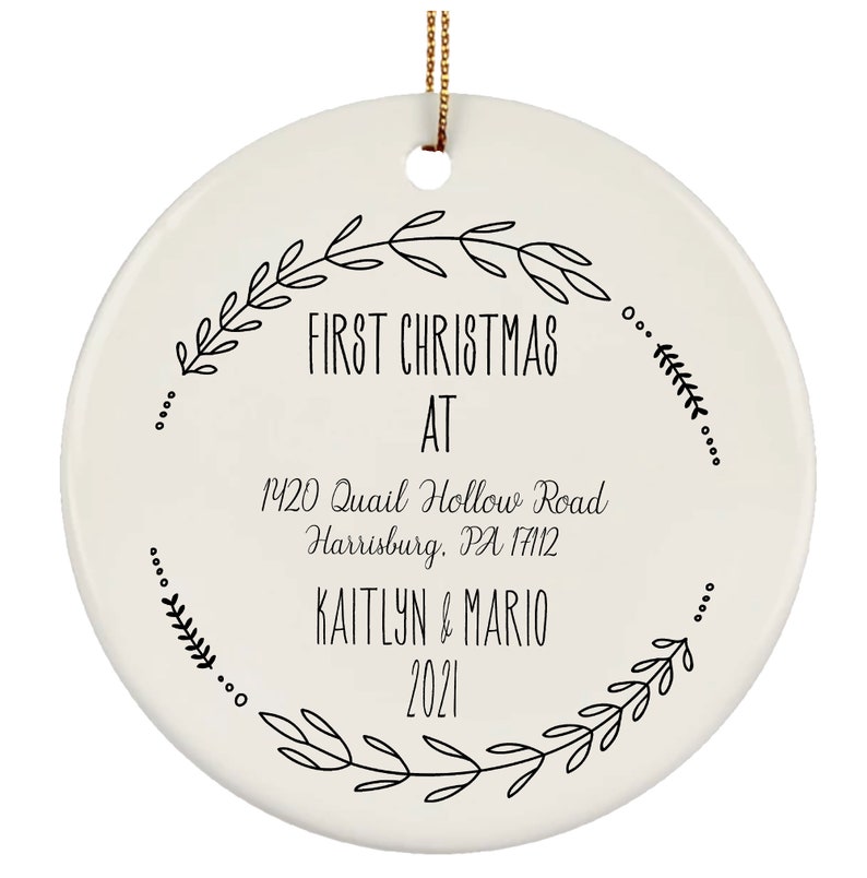 May include: White ceramic Christmas ornament with black text that reads "First Christmas at 1420 Quail Hollow Road Harrisburg, PA 17112 Kaitlyn & Mario 2021". The text is surrounded by a wreath of black leaves.