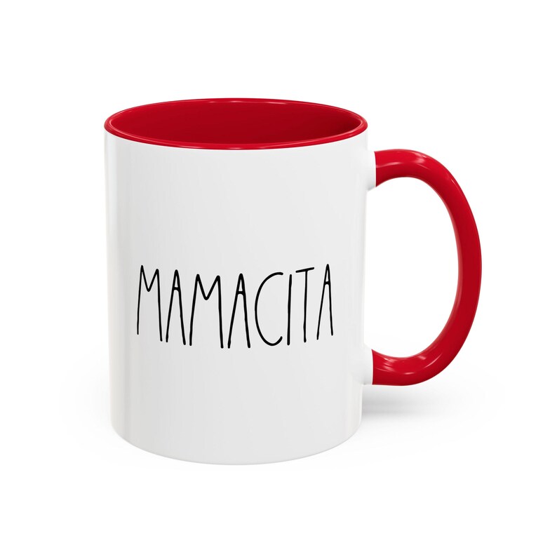 May include: White ceramic mug with a red interior and handle. The word "MAMACITA" is printed in black, handwritten-style font on the front of the mug. The mug is designed for hot or cold beverages.