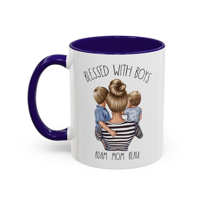 Puede incluir: Taza de cer&aacute;mica blanca con borde azul. La taza presenta un gr&aacute;fico de una mujer con dos ni&ntilde;os, con el texto "Blessed with Boys" arriba y "Adam Mom Beau" abajo.
