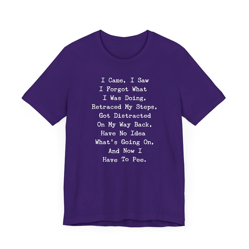 May include: A purple t-shirt with white text. The text reads: "I Came, I Saw, I Forgot What I Was Doing, Retraced My Steps, Got Distracted On My Way Back, Have No Idea What's Going On, And Now I Have To Pee."