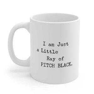 May include: White ceramic mug with black text that reads "I am Just a Little Ray of PITCH BLACK."