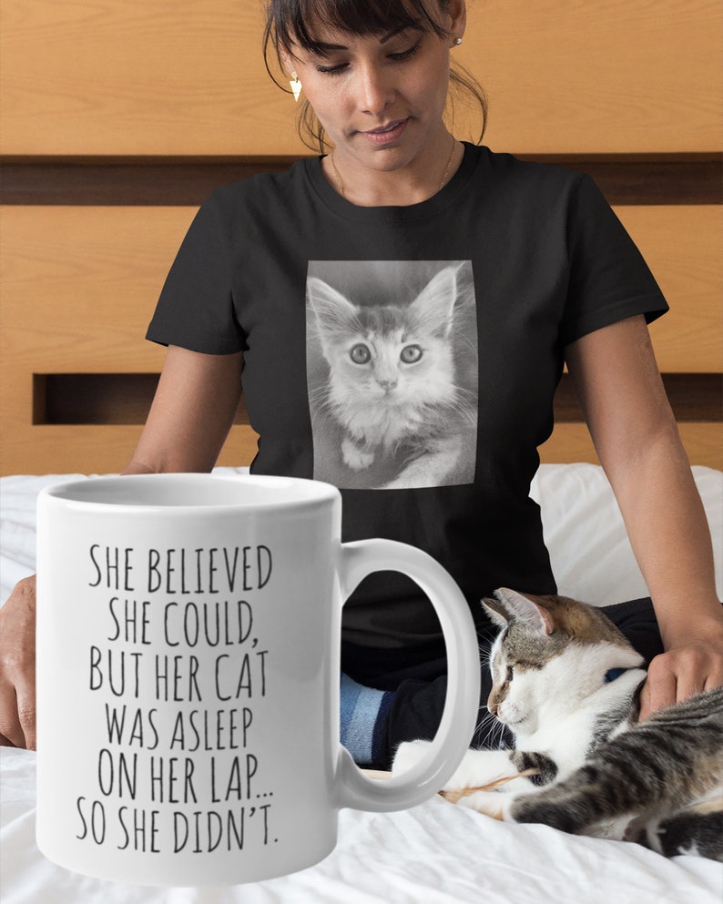 Puede incluir: Taza de cer&aacute;mica blanca con texto negro que dice "Ella cre&iacute;a que pod&iacute;a, pero su gato estaba dormido en su regazo... as&iacute; que no lo hizo."