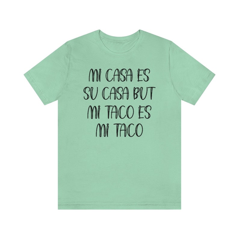Puede incluir: Una camiseta verde claro con el texto "Mi casa es su casa but mi taco es mi taco" impreso en negro.