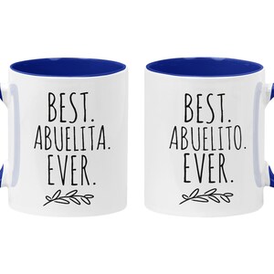 Peut inclure: Deux tasses en c&eacute;ramique blanche avec des bords bleus. La tasse de gauche dit "Best Abuelita Ever." La tasse de droite dit "Best Abuelito Ever."