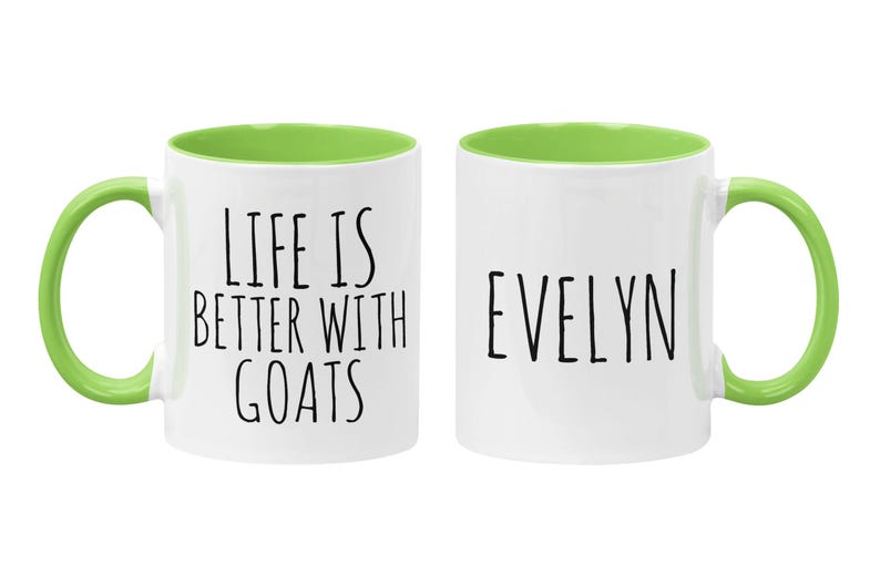May include: Two white ceramic mugs with green rims and handles. One mug says "Life is better with goats" and the other mug says "Evelyn".