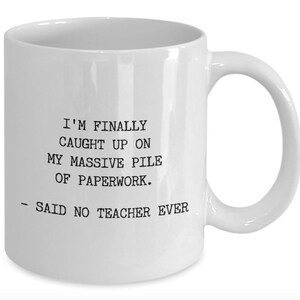 May include: White ceramic coffee mug with black text that reads: "I'm finally caught up on my massive pile of paperwork. - Said no teacher ever."