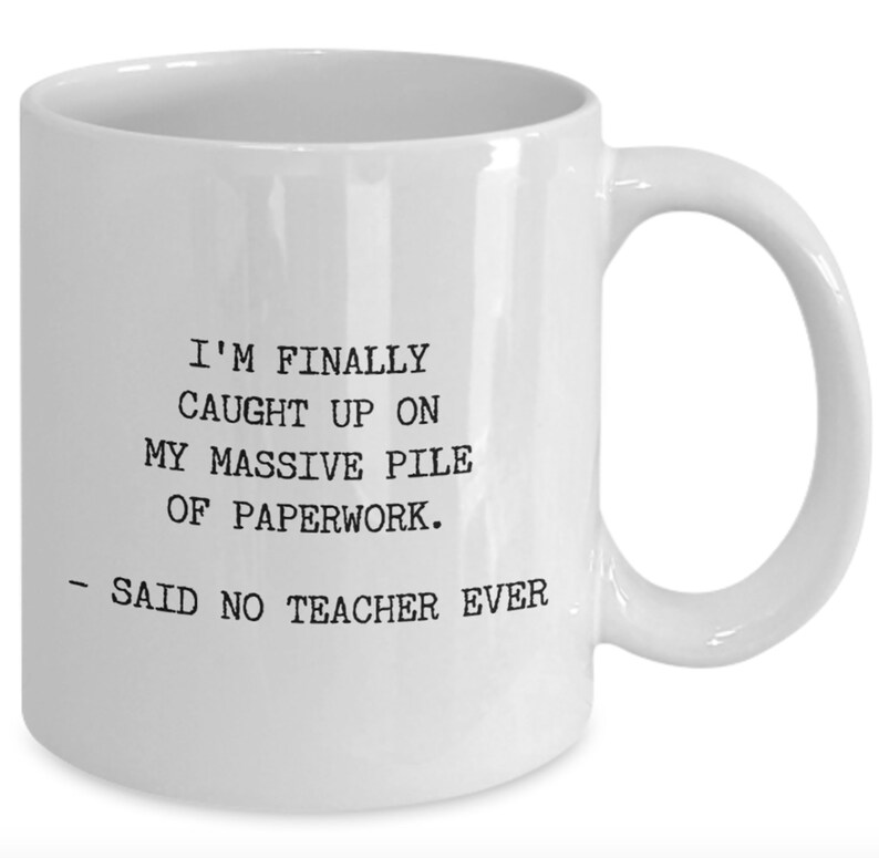 May include: White ceramic coffee mug with black text that reads: "I'm finally caught up on my massive pile of paperwork. - Said no teacher ever."