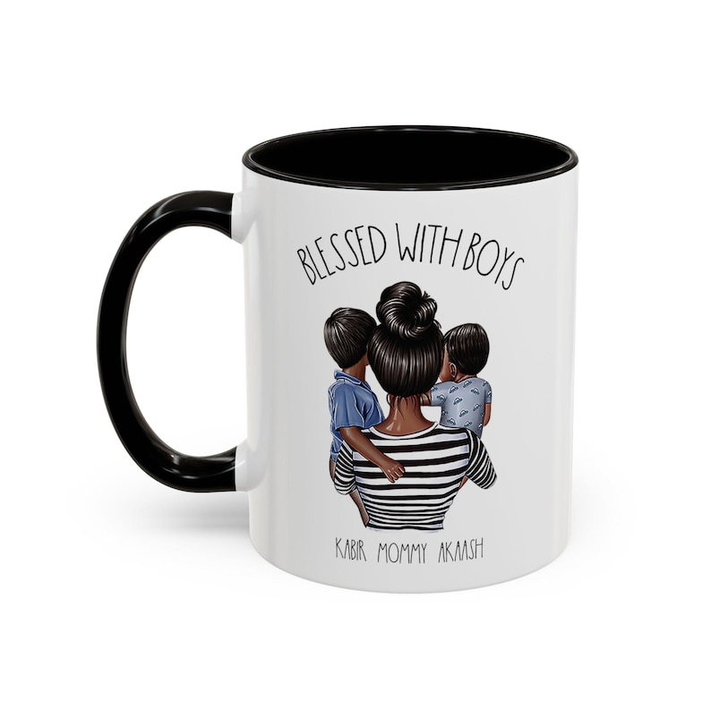 Puede incluir: Taza de cer&aacute;mica blanca con borde y asa negros. La taza tiene una ilustraci&oacute;n en blanco y negro de una madre con dos hijos. El texto "Blessed with Boys" est&aacute; impreso en la taza, junto con los nombres "Kabir, Mommy, Aakash".
