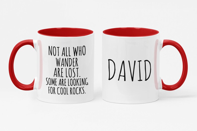 K&ouml;nnte beinhalten: Zwei wei&szlig;e Keramikbecher mit rotem Innenraum. Ein Becher tr&auml;gt den Text "NOT ALL WHO WANDER ARE LOST. SOME ARE LOOKING FOR COOL ROCKS." Der andere Becher tr&auml;gt den Namen "DAVID" aufgedruckt.