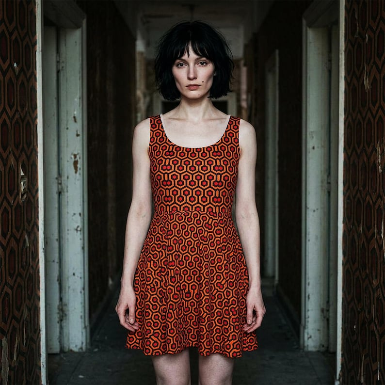 May include: A sleeveless dress featuring a repeating geometric pattern in shades of orange, red, and dark brown. The garment has a scoop neckline and a fitted bodice that transitions into a flared skirt, showcasing a consistent hexagonal motif.