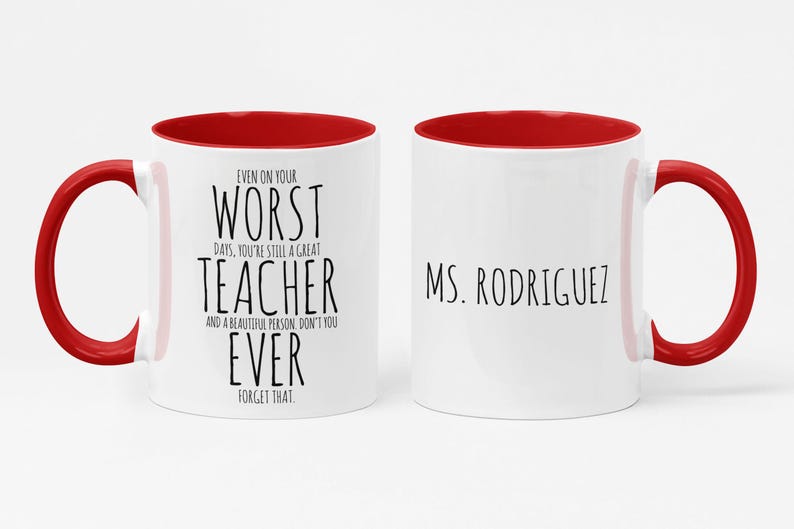 May include: White ceramic mug with a red interior and handle. The mug features the text "EVEN ON YOUR WORST DAYS, YOU'RE STILL A GREAT TEACHER" on one side and "MS. RODRIGUEZ" on the other side, in black font.