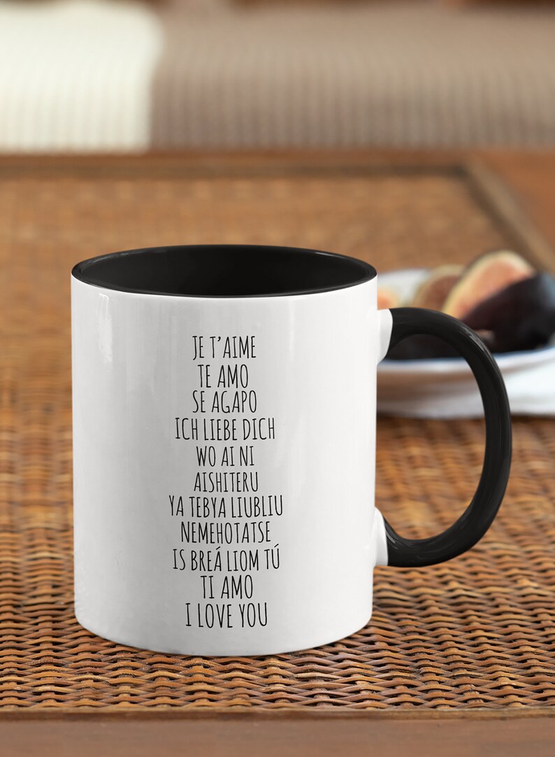 May include: White ceramic mug with a black rim and handle. The mug has black text that reads "Je t'aime, Te amo, Se agapo, Ich liebe dich, Wo ai ni, Aishiteru, Ya tebya liubliu, Nemehotatse, Is brea liom tu, Ti amo, I love you."