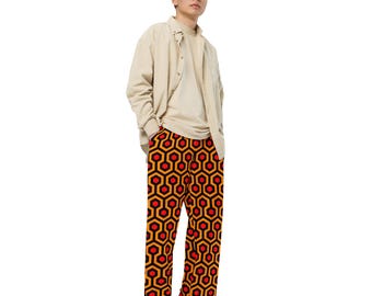 May include: A person wearing a beige button-down shirt and orange and black patterned pants. The pants have a geometric pattern of hexagons.