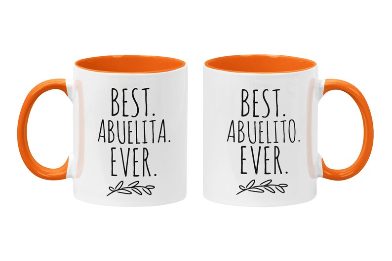 Peut inclure: Deux tasses en c&eacute;ramique blanche avec des bords orange. La tasse de gauche dit "Best Abuelita Ever." La tasse de droite dit "Best Abuelito Ever."