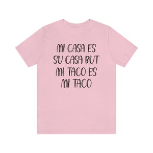 Puede incluir: Camiseta rosa con el texto "Mi casa es su casa but mi taco es mi taco" impreso en negro.