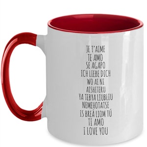 May include: White ceramic coffee mug with a red rim and handle. The mug has black text that reads "Je t'aime", "Te amo", "Se agapo", "Ich liebe dich", "Wo ai ni", "Aishiteru", "Ya tebya liubliu", "Nemehotatse", "Is bre&aacute; liom t&uacute;", "Ti amo", "I love you".