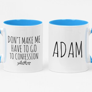 May include: Two white ceramic mugs with blue interiors and handles. One mug has the text "DON'T MAKE ME HAVE TO GO TO CONFESSION" and a small leaf design. The other mug has the name "ADAM" in black text.